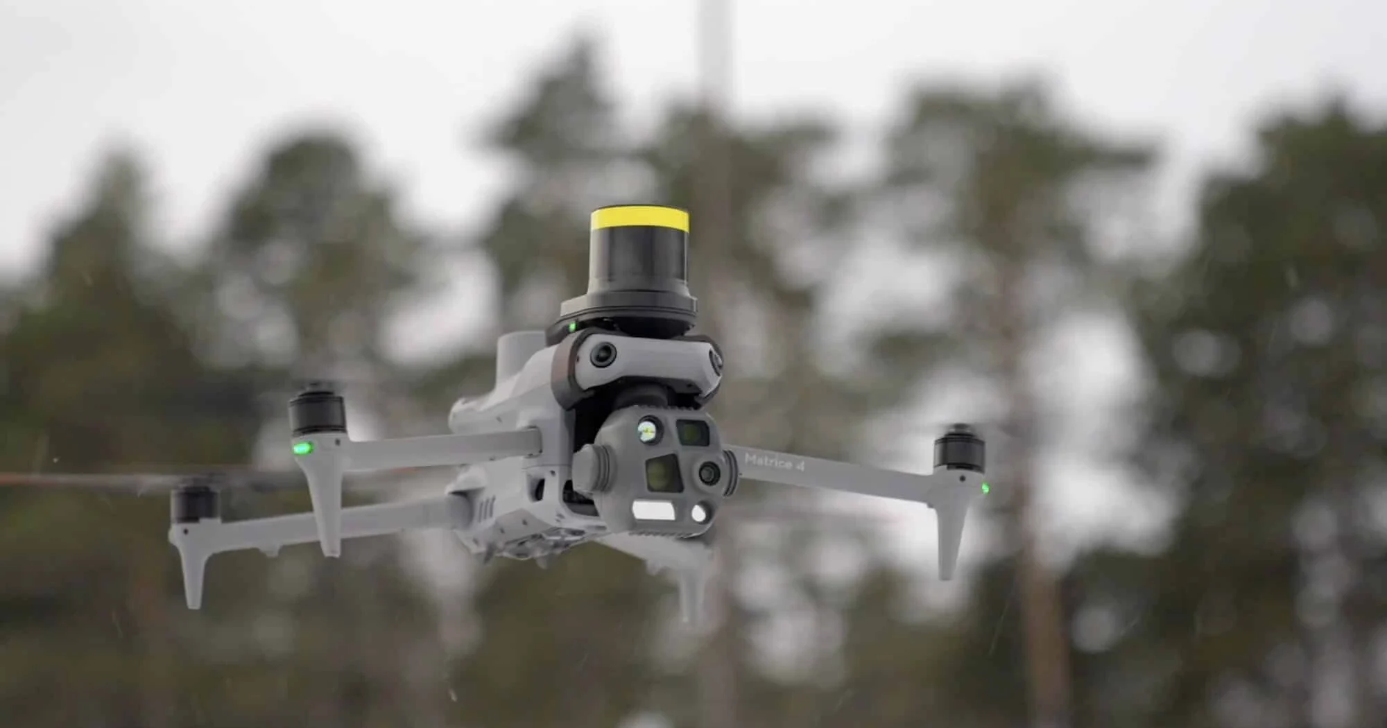 En primer plano el DJI Matrice 4T volando y de fondo un bosque