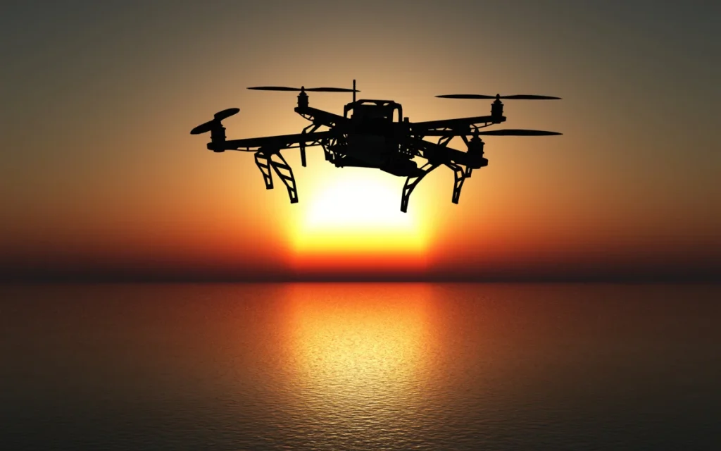 dron multirrotor volando en silueta sobre el mar al atardecer