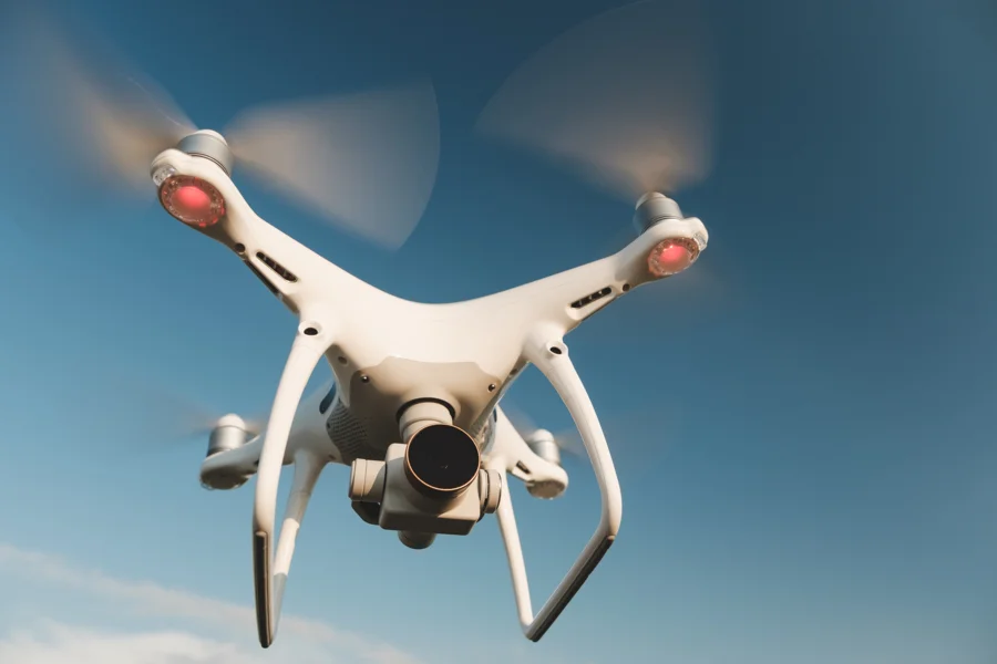 Dron cuadricóptero en vuelo mostrando cámara con gimbal, brazos y hélices en movimiento