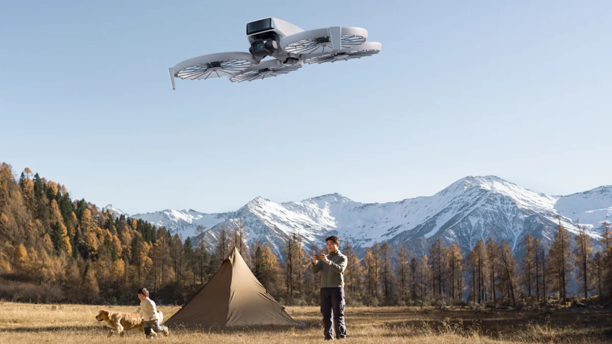 Imagen de un hombre con un niño mientras controlan el DJI Flip y en segundo plano la imagen de una casa de campaña y un paisaje de bosque y montanas