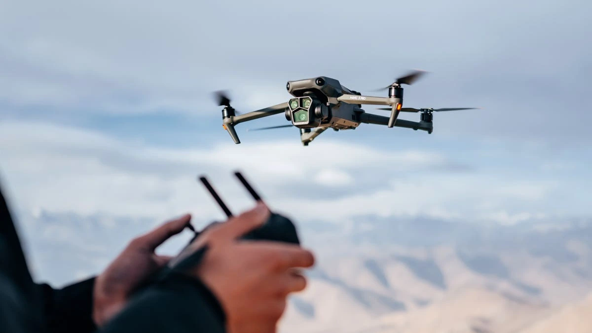 En primer plano una persona piloteando un DJI Mavic 3 Cine Pro y segundo plano el dron