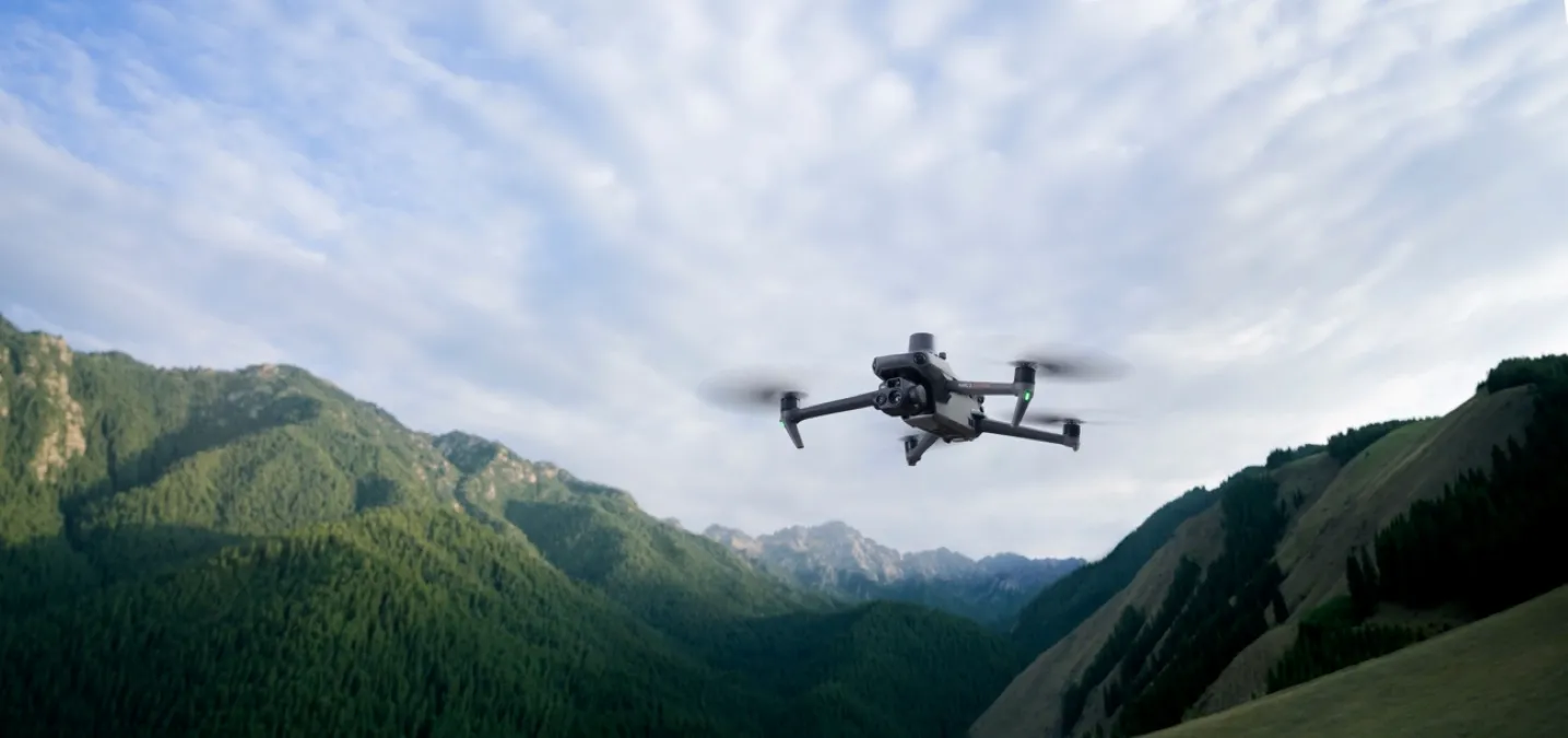 imagen del mavic 3 entrepiso mientras sobrevuela un campo y de fondo una montana