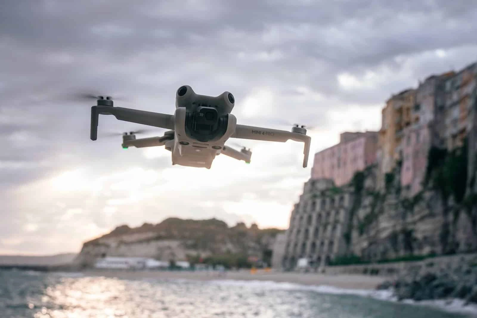 El DJI Mini 4 Pro volando cerca del agua mientras en segundo plano un atardecer