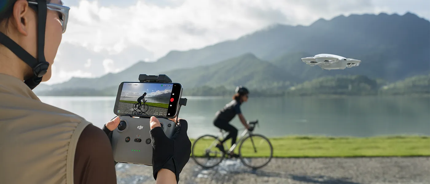 DJI Neo grabando mientras se realiza un viaje en bicicleta, de fondo una montana y lago