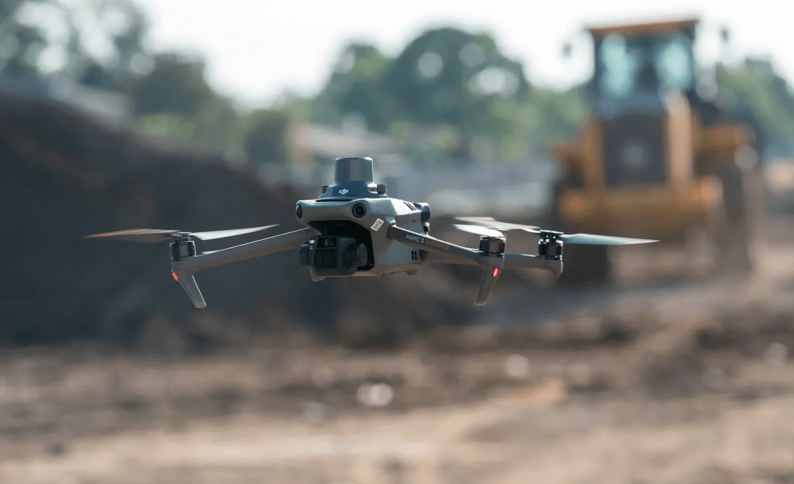 DJI Mavic 3E volando en una construcción y de fondo un tractor desenfocado