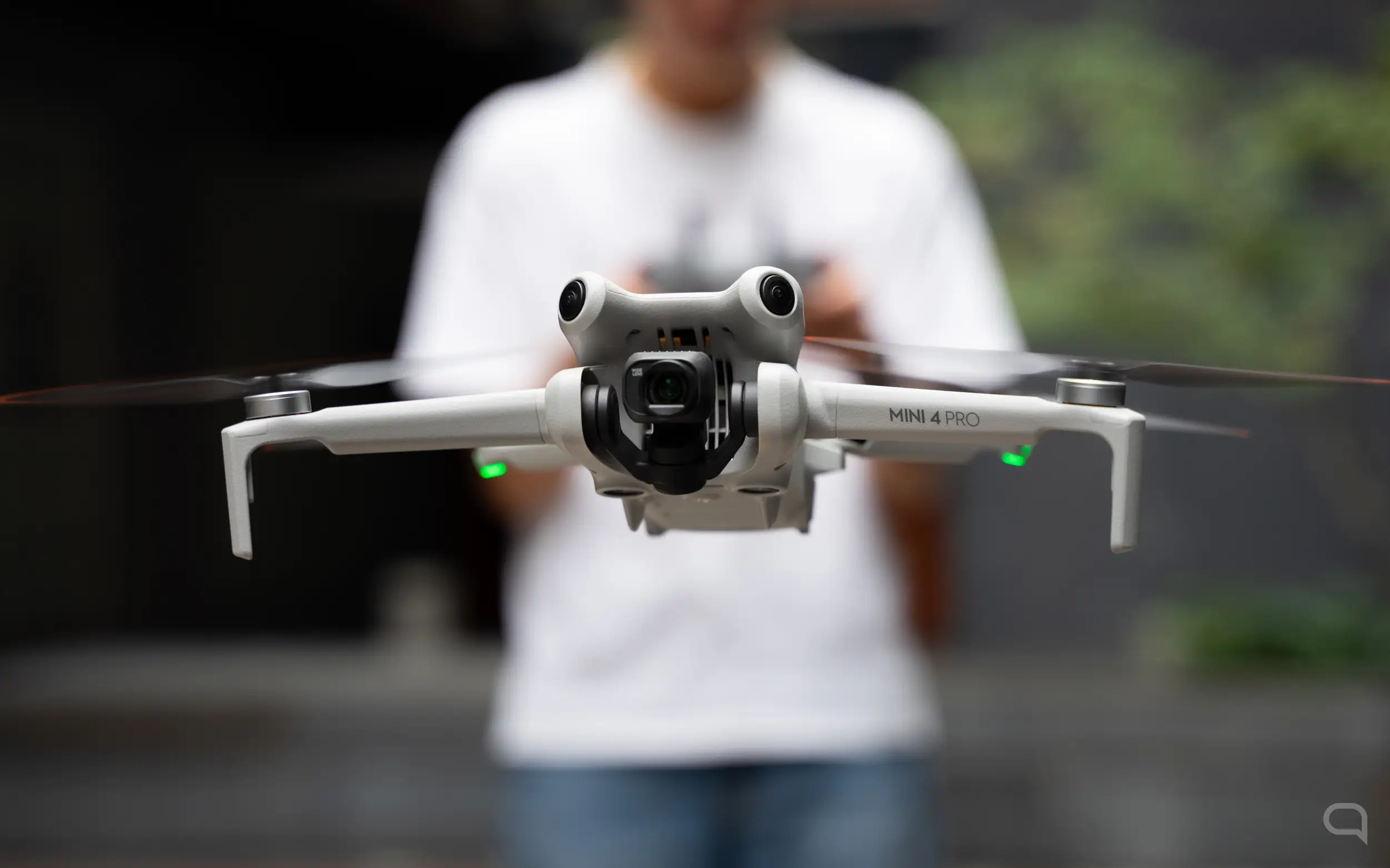 En primer plano el DJI Mini 4 en primer plano y una persona desenfocadla de fondo 
