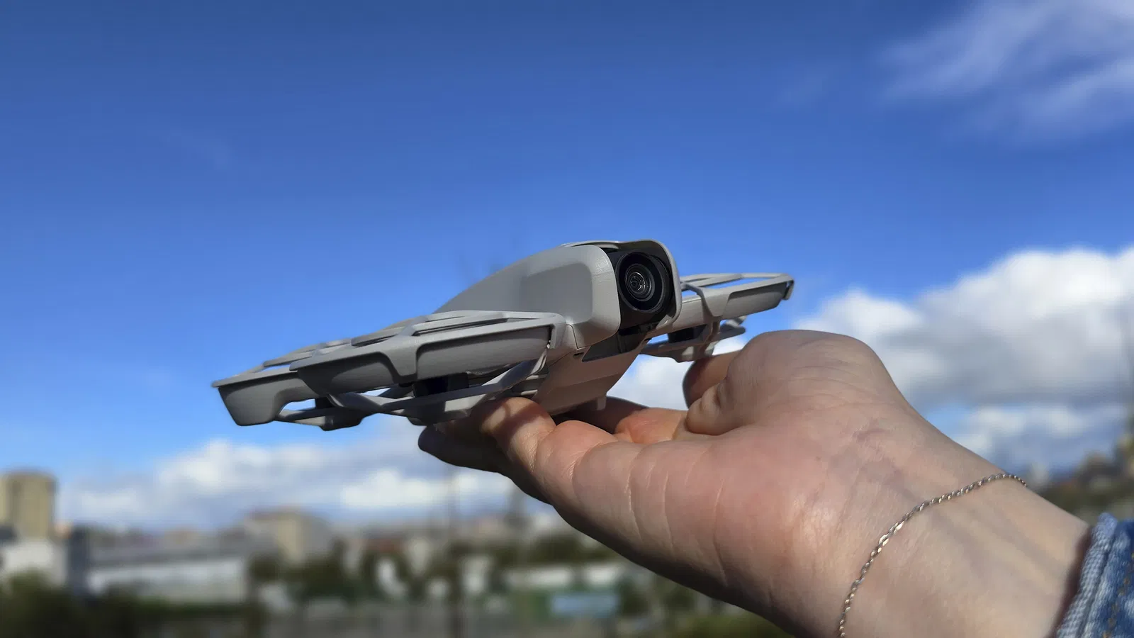 Imagen del DJI Neo aterrizando en una mano y de fondo un paisaje