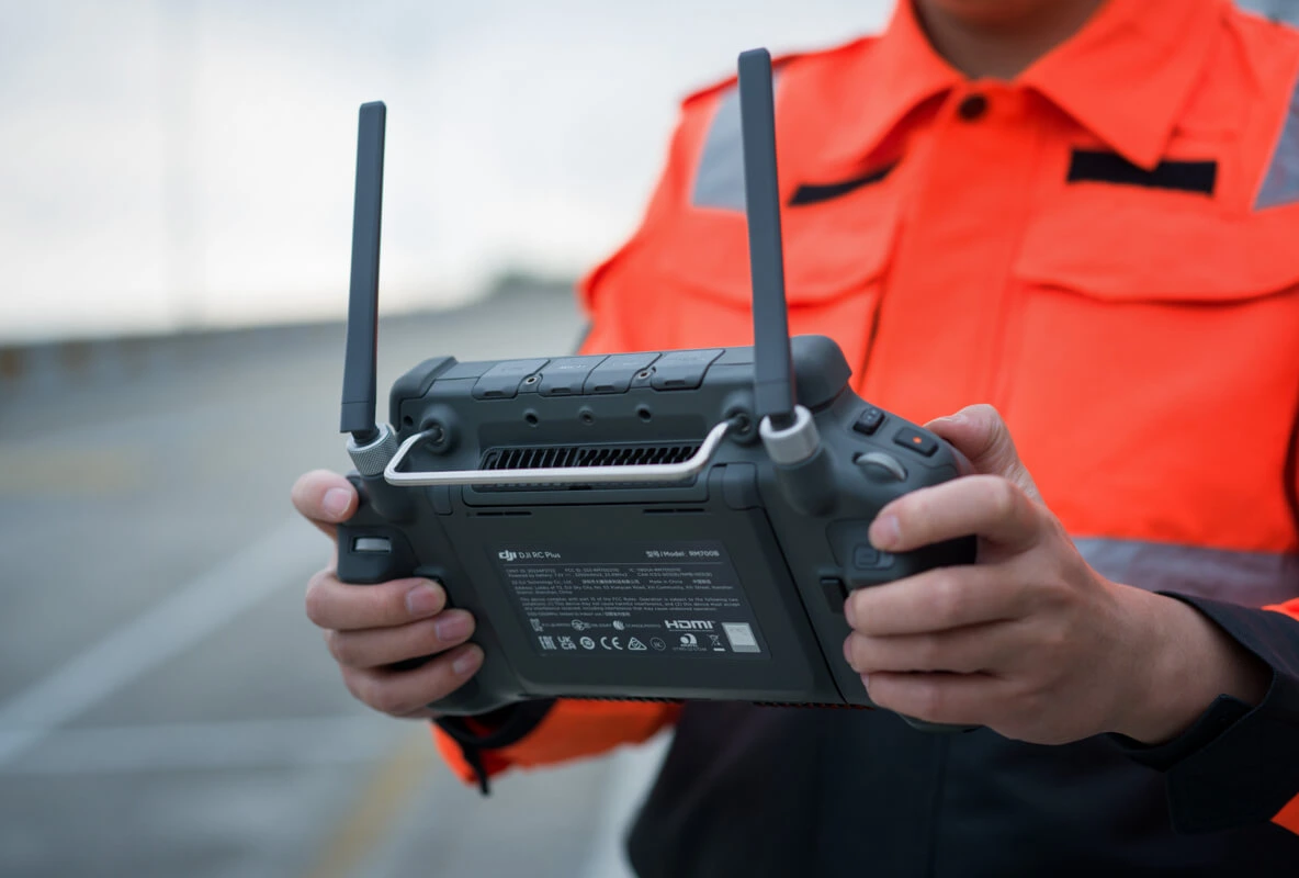 primer plano de un control de dron y desenfocado una persona piloteando