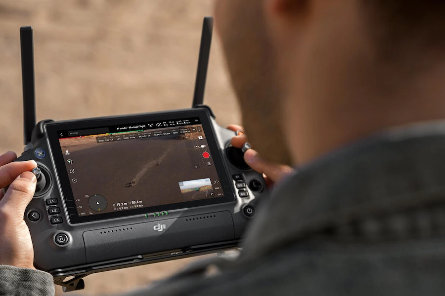 Controlador de dron DJI mostrando en pantalla una transmisión en vivo con alta calidad de imagen durante una misión aérea.