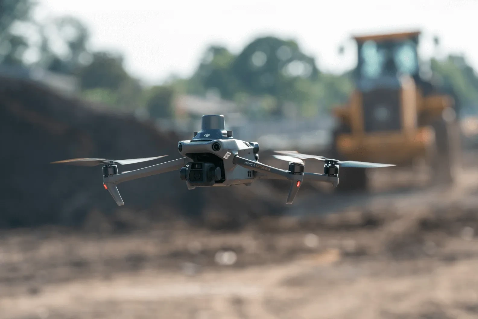 Imagen del DJI Mavic 3 Enterprise volando en una construcción, de fondo un terreno 
